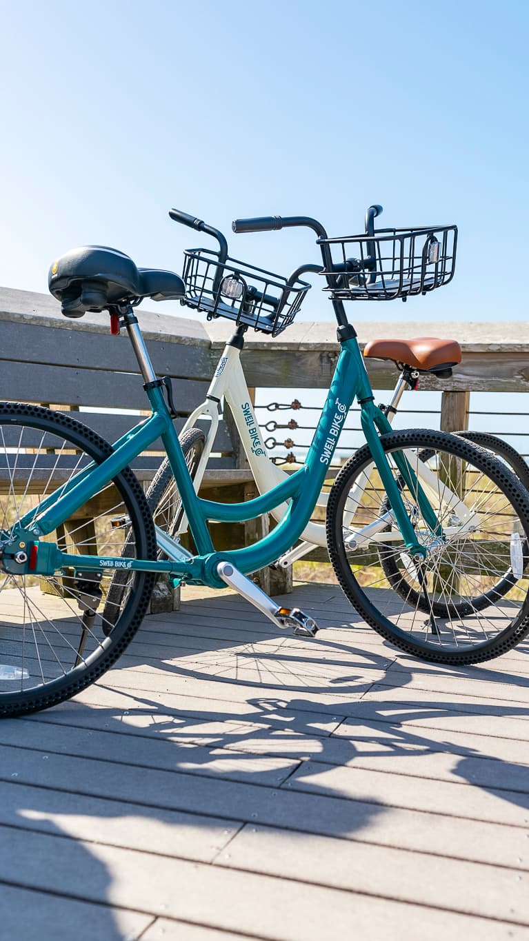 Two Swell bikes parked against a boardwalk railing