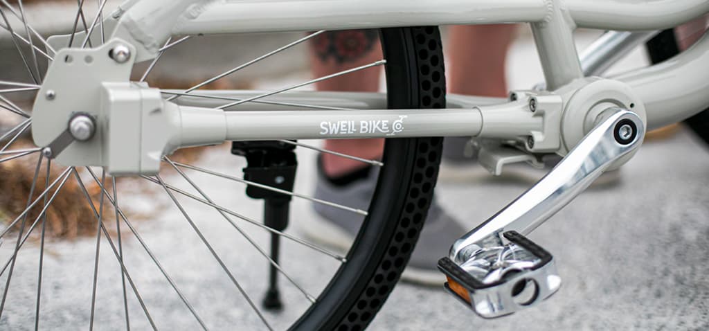 Close-up of the enclosed shaft drive and honeycomb rear tire on a cream Swell bike