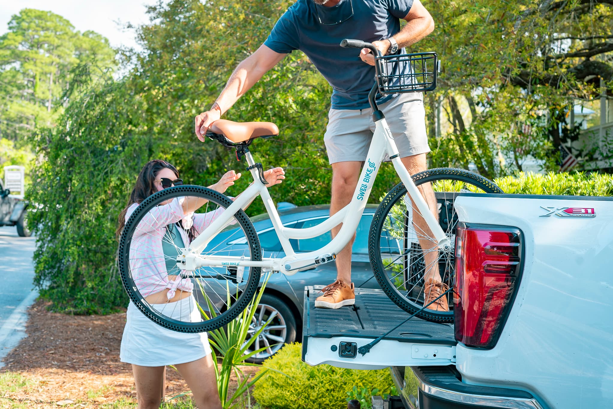 A couple unloading a Swell bike from the back of a pickup truck